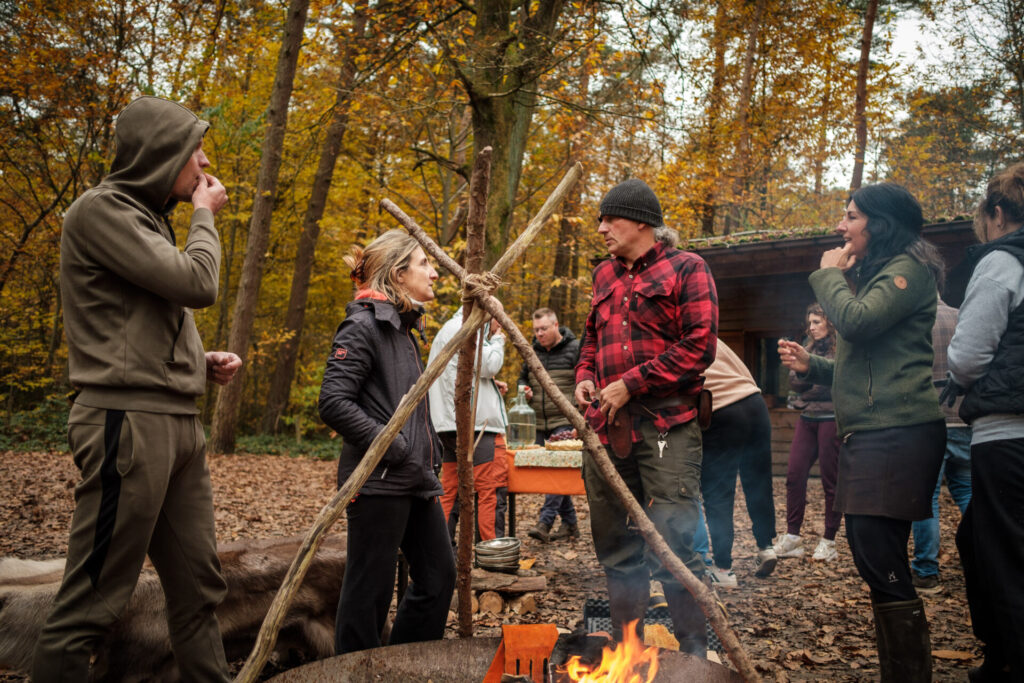 Kampvuur waarrind collega's samen eten in het bos